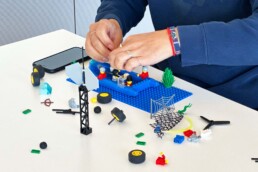 Hände einer Frau, die in einem LEGO Serious Play Workshop Lego Steine zusammensetzen.